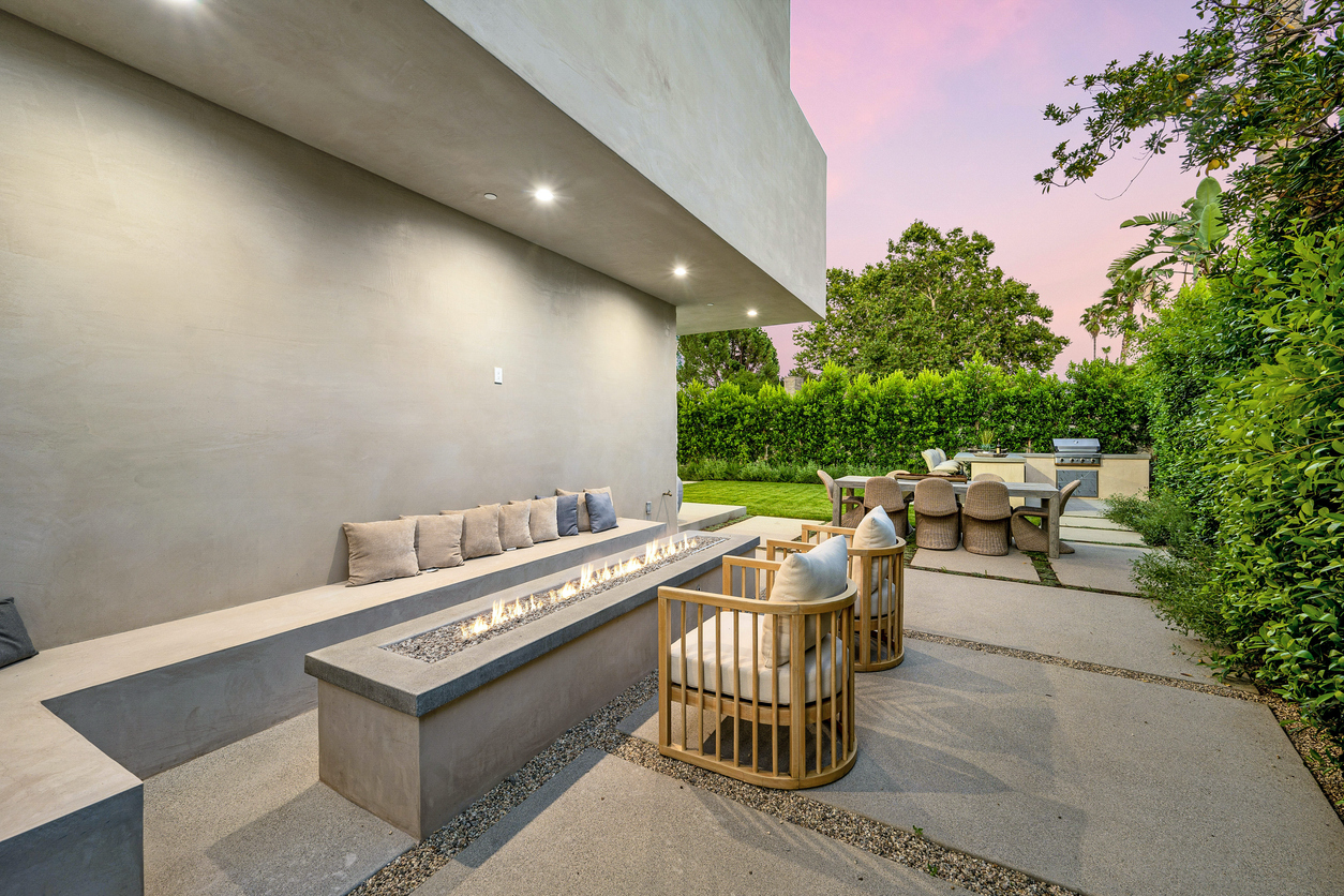 An image showcasing a beautifully constructed patio featuring a stylish firepit and a stunning concrete bench, emphasizing the elegance of patio construction and fire pit integration in outdoor design.