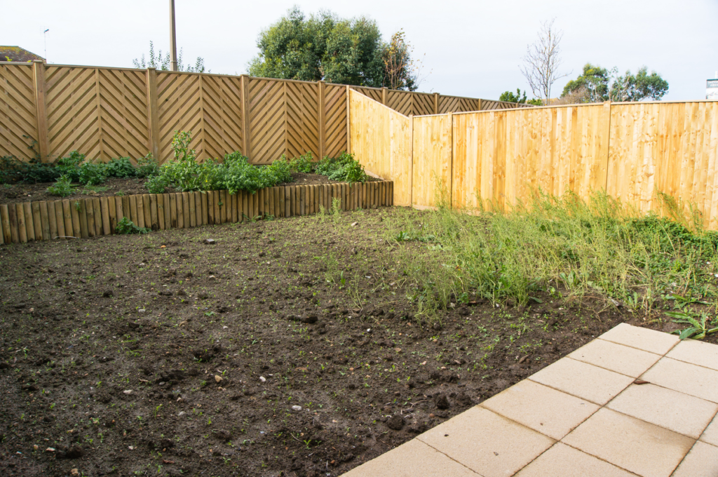 An unsightly backyard with overgrown grass and unutilized space, highlighting the need for a backyard remodeling project to transform the area into a functional and inviting outdoor space.