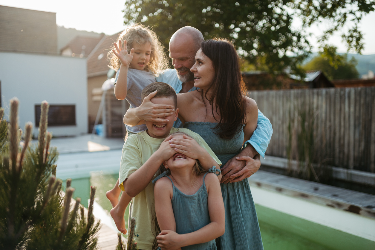 A delighted family enjoying their remodeled backyard, spending quality time by the pool and laughing together, showcasing the success of their backyard remodeling project.