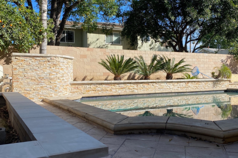 Image showcasing a beautiful pool with stone veneer garden walls and a custom stamped concrete patio.