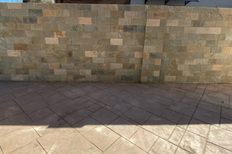Image showcasing a stunning stamped concrete patio with a charming masonry wall.