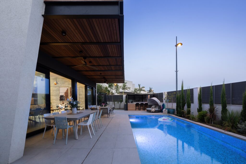 Image showcasing a stunning indoor-outdoor patio with a backyard swimming pool.