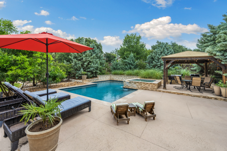 Image showcasing a stunning backyard with a concrete patio and pool.