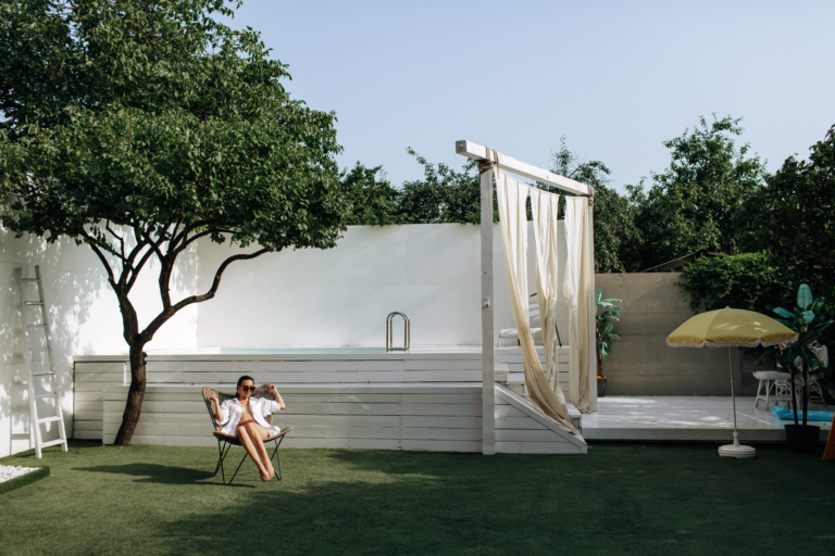 Image showcasing a woman enjoying and relaxing in her backyard patio by a pool.