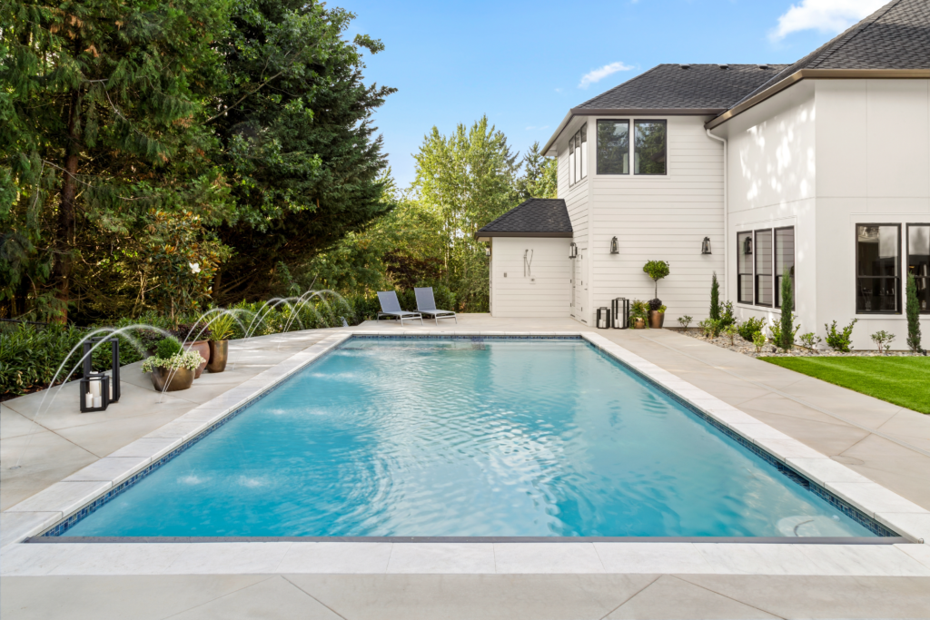 Image showcasing an elaborate backyard pool with stone flooring.