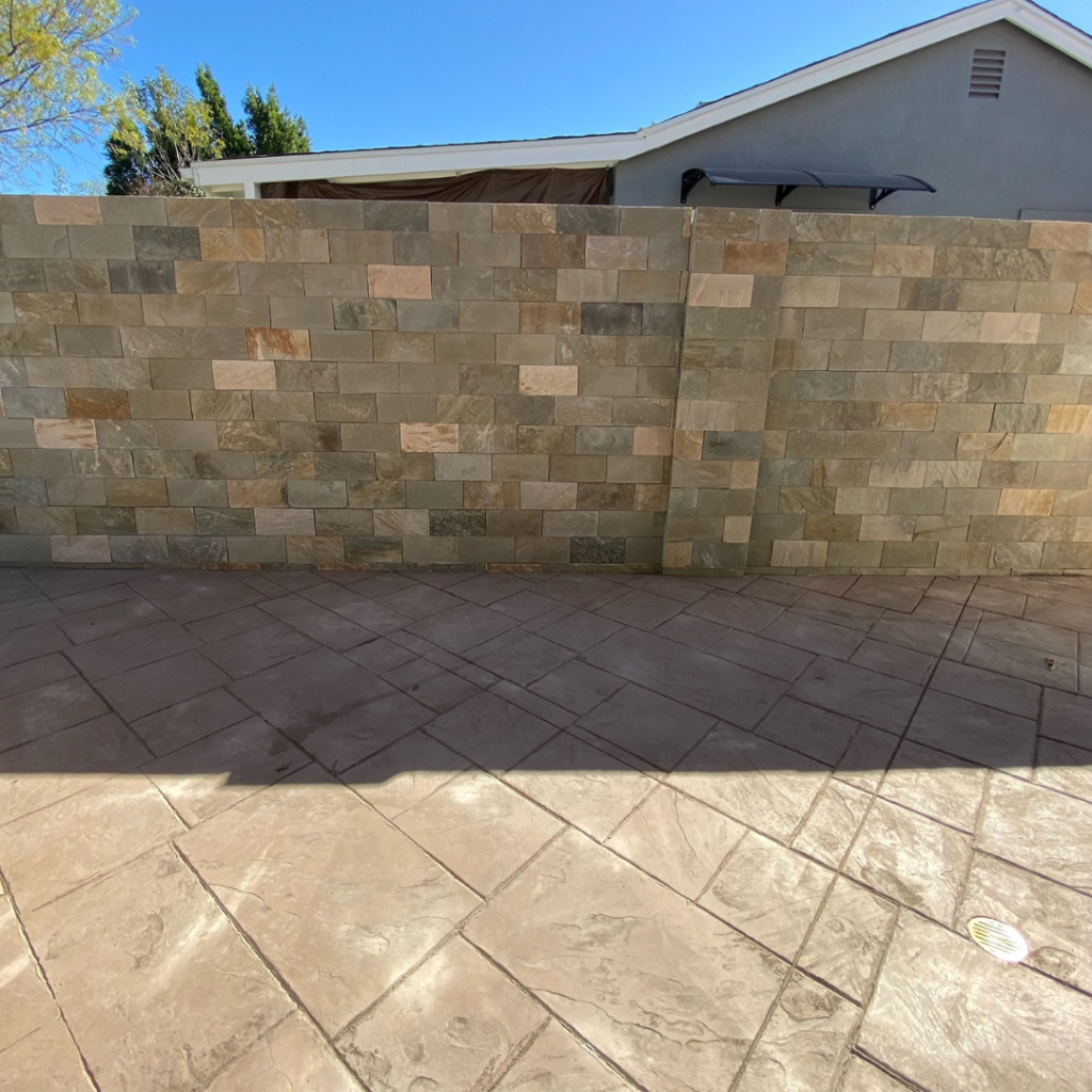 Image showcasing a stamped concrete patio and a stunning stone veneer wall.